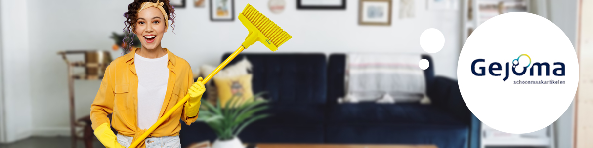 Een lachende vrouw met een gele vikan bezem in haar hand, in een woonkamer.